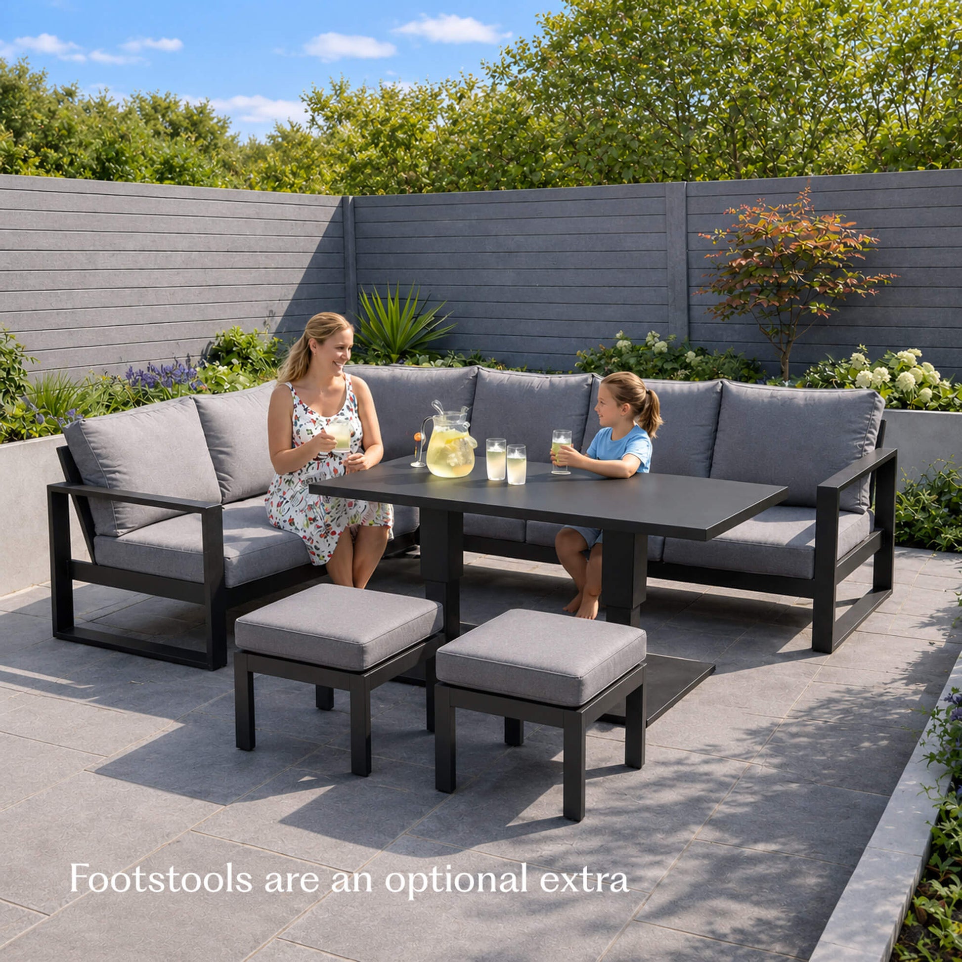 Mother and daughter sitting on a Como dark grey L-shaped outdoor furniture corner set with matching stool set.
