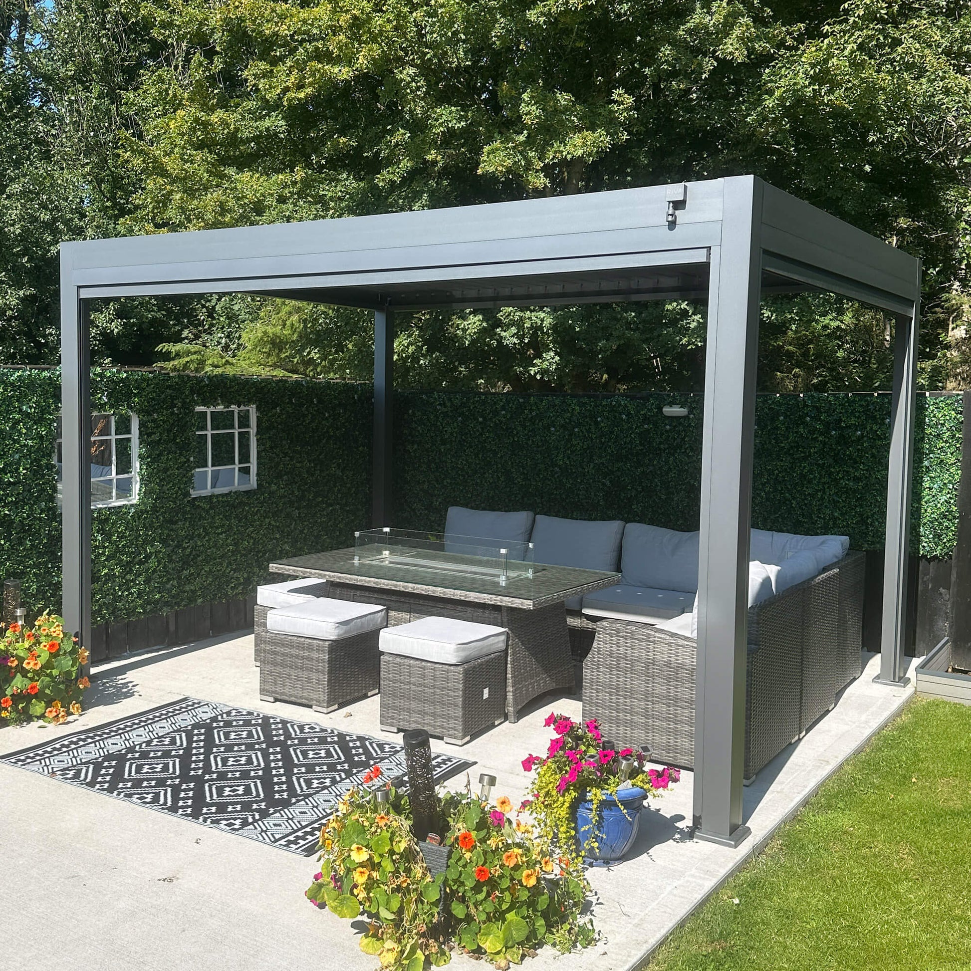 Outdoor patio area with a pergola, seating, and flowers in a garden setting.